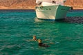 Two young ladies are snorkeling in clean water over reef near the moored yacht. Travel and tourism concept